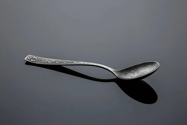 Old nickel silver spoon on a reflective surface