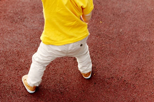 白天在户外散步的儿童穿着白色裤子和黄色 T恤的特写镜头 — 图库照片