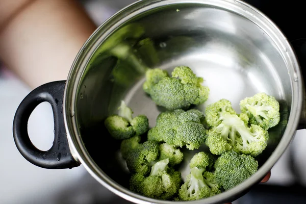 Closeup of iron pan with pile of broccoli over dark background