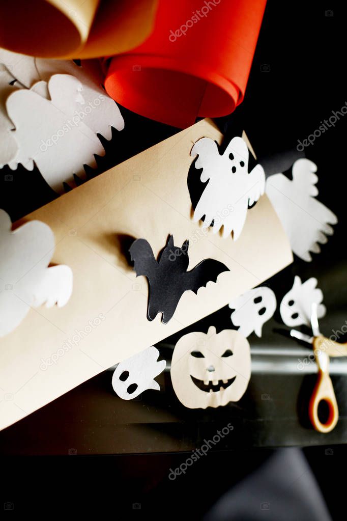 Closeup view of Halloween paper decorations on table with scissors and pieces of colored paper  