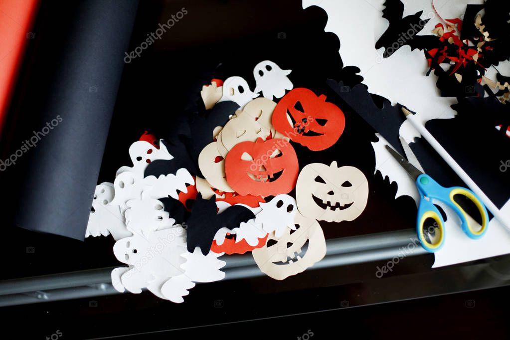 Closeup view of Halloween paper decorations on table with scissors and pieces of colored paper  