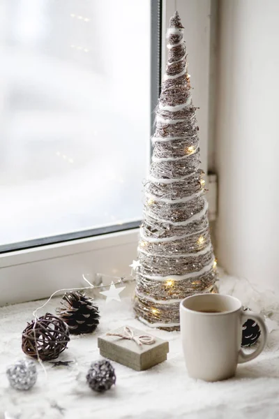 Holidays celebration at home concept, Christmas tree, decoration and coffee cup against winter window. Holiday flat lay concept