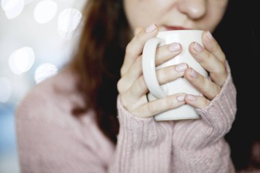 Mavi jeans ve kış kazak holding fincan çay, arka plan bulanık giyen güzellik esmer kadın portresi portre
