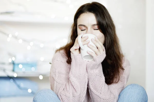 美容ブルネット女性ブルー ジーンズと冬のセーター持株杯熱いお茶 背景をぼかした写真のポートレート クローズ アップ — ストック写真