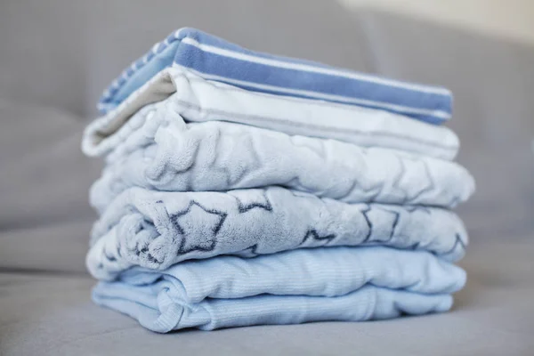 Closeup of pile of blue clothes placed on grey sofa