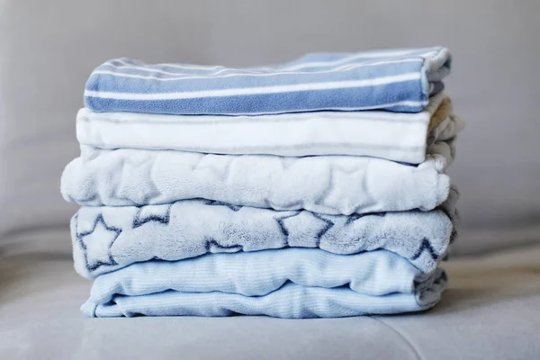 Closeup of pile of blue clothes placed on grey sofa