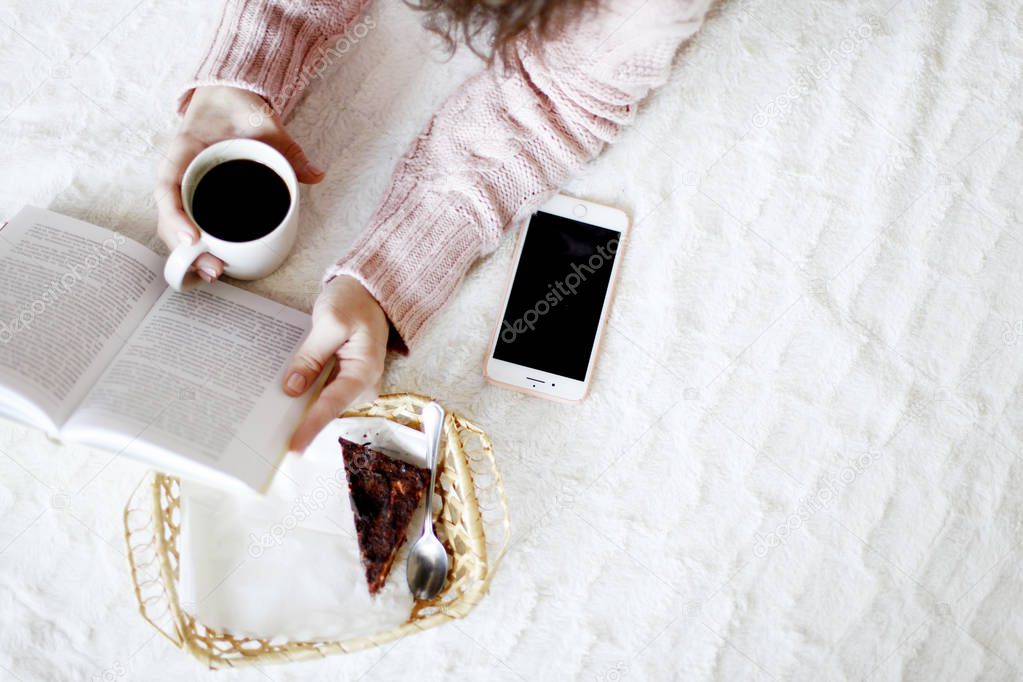 Elevated view of beauty brunette woman wearing winter sweater reading book and holding cup of coffee