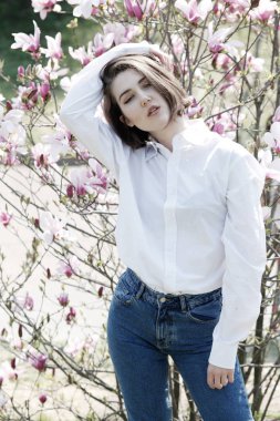 Genç güzel kadın çiçek açan Manolya bahçede poz model.