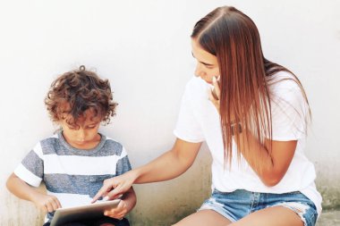 Anne ve varoluş oğlu tablet ve smartphone kullanarak. Okul için trendy aile bak Modern aile, arka