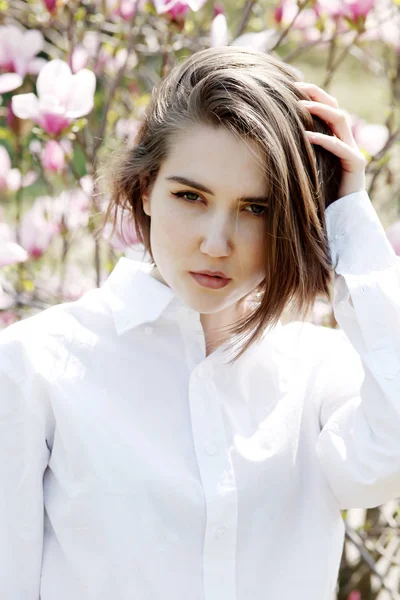 Joven hermosa modelo mujer posando en el jardín de magnolias florecientes . —  Fotos de Stock