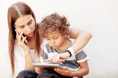 Anne ve varoluş oğlu tablet ve smartphone kullanarak. Okul için trendy aile bak Modern aile, arka