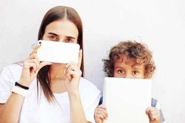 Mother and preteen son using tablet and smartphone. Modern family, back to school, trendy family look