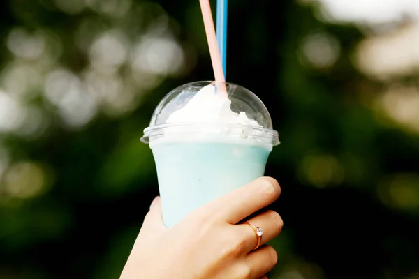 Frau mit Milchcocktail und Makronen in der Hand — Stockfoto