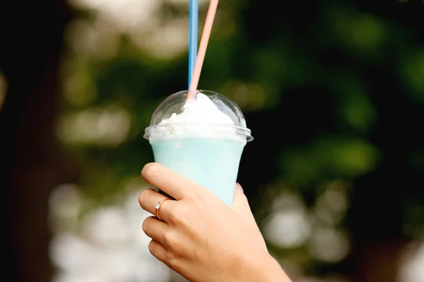 Vrouw met melk cocktail en macaroon in handen — Stockfoto