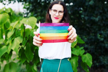 Lgbt hakları kavramı, el, doğanın zemininde, Lgbt bayrağı tutar. Doğada Lgbt bayrağı olan genç bir kız. 