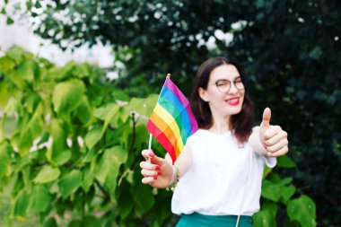 Lgbt hakları kavramı, el, doğanın zemininde, Lgbt bayrağı tutar. Doğada Lgbt bayrağı olan genç bir kız. 