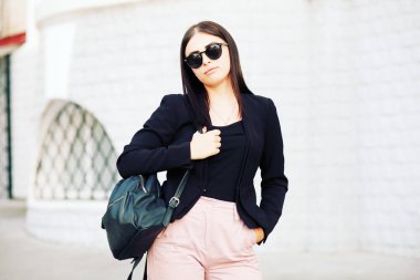 Güzel genç öğrenci hippi kız sağlıklı düz saçlı bir siyah ceket ve sırt çantası takmış. Sokak stili.