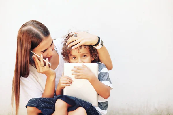Mother and preteen son using tablet and smartphone. Modern family, back to school, trendy family look