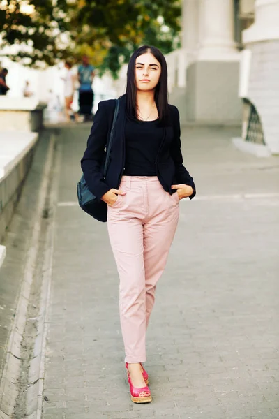 Güzel genç öğrenci hippi kız sağlıklı düz saçlı bir siyah ceket ve sırt çantası takmış. Sokak stili.