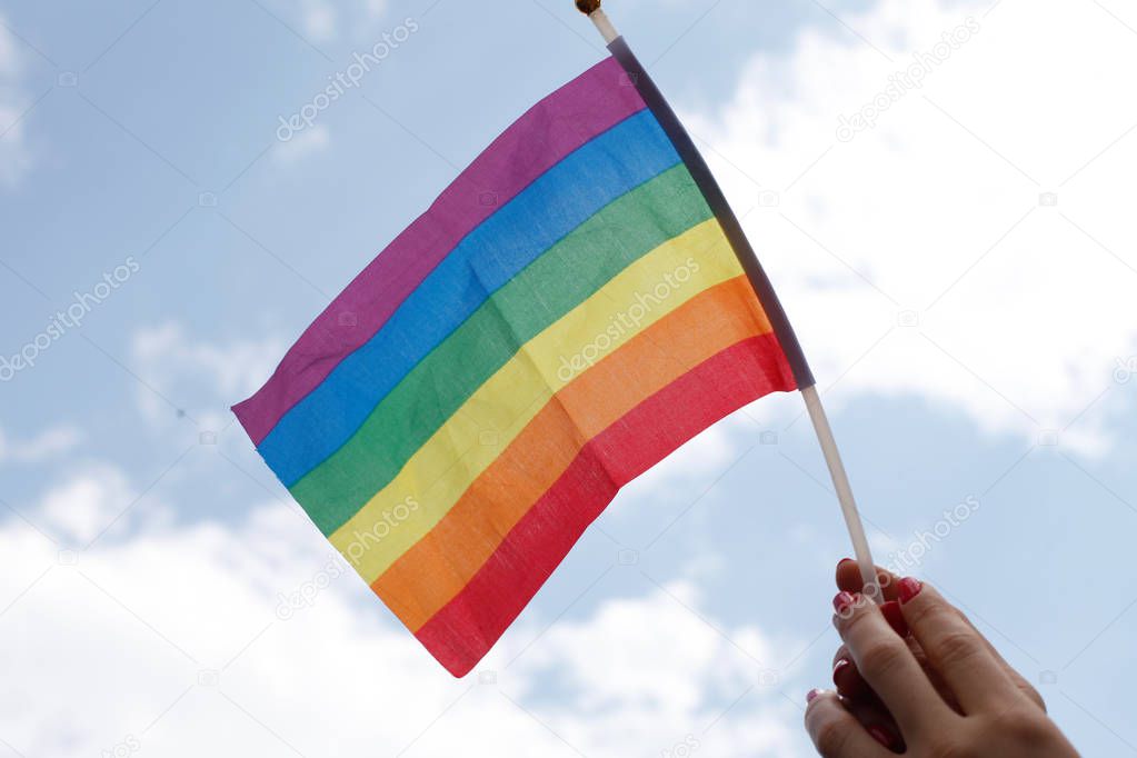 female hand waves gay pride LGBT rainbow flag 