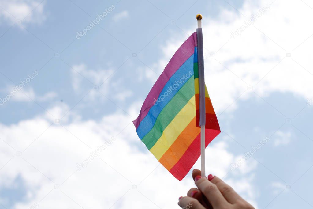 female hand waves gay pride LGBT rainbow flag 