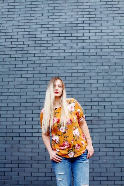 Artı boyutu kadın sarı çiçek gömlek ve mavi kot gülümseyen giyiyor.