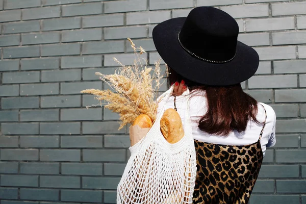 woman with bread in her knitted bag