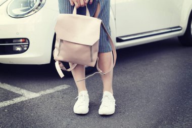 Araba ile poz pembe sırt çantası ile denim elbiseli genç kadın