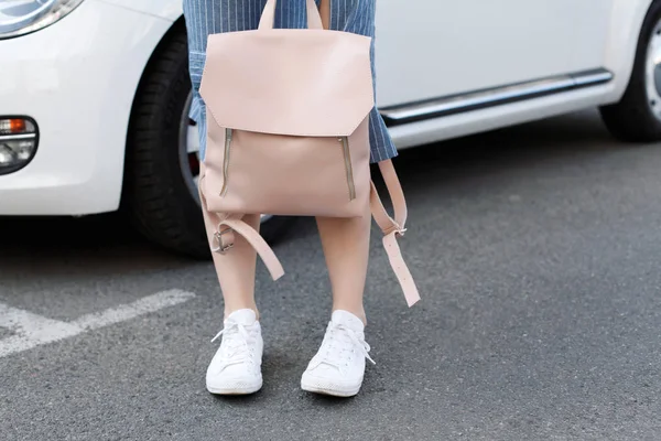 Araba ile poz pembe sırt çantası ile denim elbiseli genç kadın