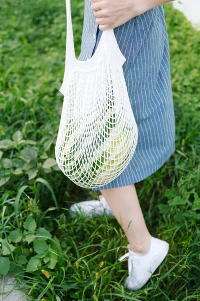Young woman carrying watermelon in knitted bag