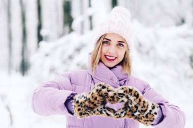 Kabarık eldivenli genç bir kadın kalbini gösteriyor.