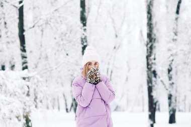 Genç bir kadın kış sahnesinde poz veriyor.