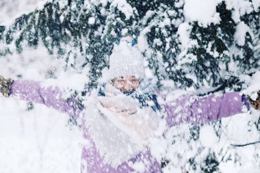Genç mutlu kadın parkta karla oynuyor.
