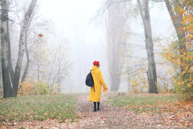 Sonbahar parkında sarı yağmurluk giyen bir kadının dikiz aynası.
