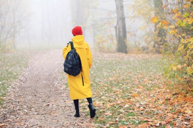 Sonbahar parkında sarı yağmurluk giyen bir kadının dikiz aynası.