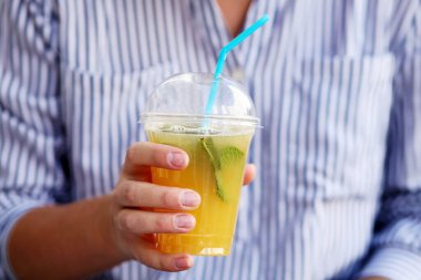 Elinde bir bardak taze yeşil meyve püresi tutan kadın.