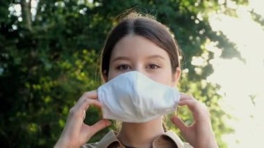 Kız giyiniyor ve sokakta maskesini çıkarıyor.