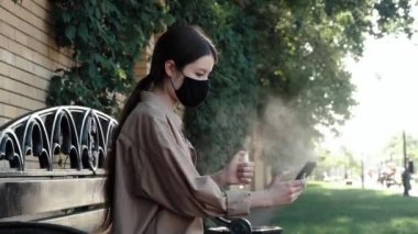 Sokakta cep telefonu spreyiyle dezenfekte eden bir kız.