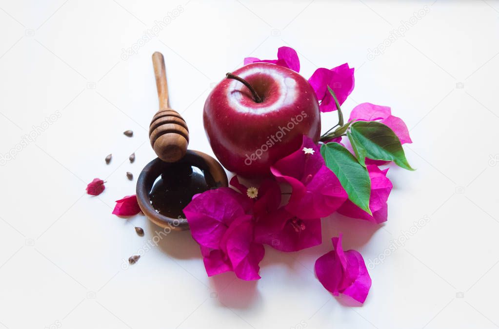 Rosh Hashanah Jewish holiday concept - red apple, wooden dipper, saucer of honey on white background with pink flowers. Traditional holiday symbols