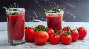 Bir mermer zemin, kopya alanı üzerine su damla biberiye dalı ve taze olgun kırmızı kiraz domates ile süslenmiş domates suyu kaplı