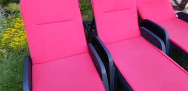 Rahatlama ve eğlence için hazır zemin döşeme boş kırmızı güneşlenme yatakları.