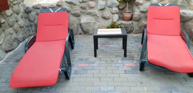 Rahatlama ve eğlence için hazır zemin döşeme boş kırmızı güneşlenme yatakları.