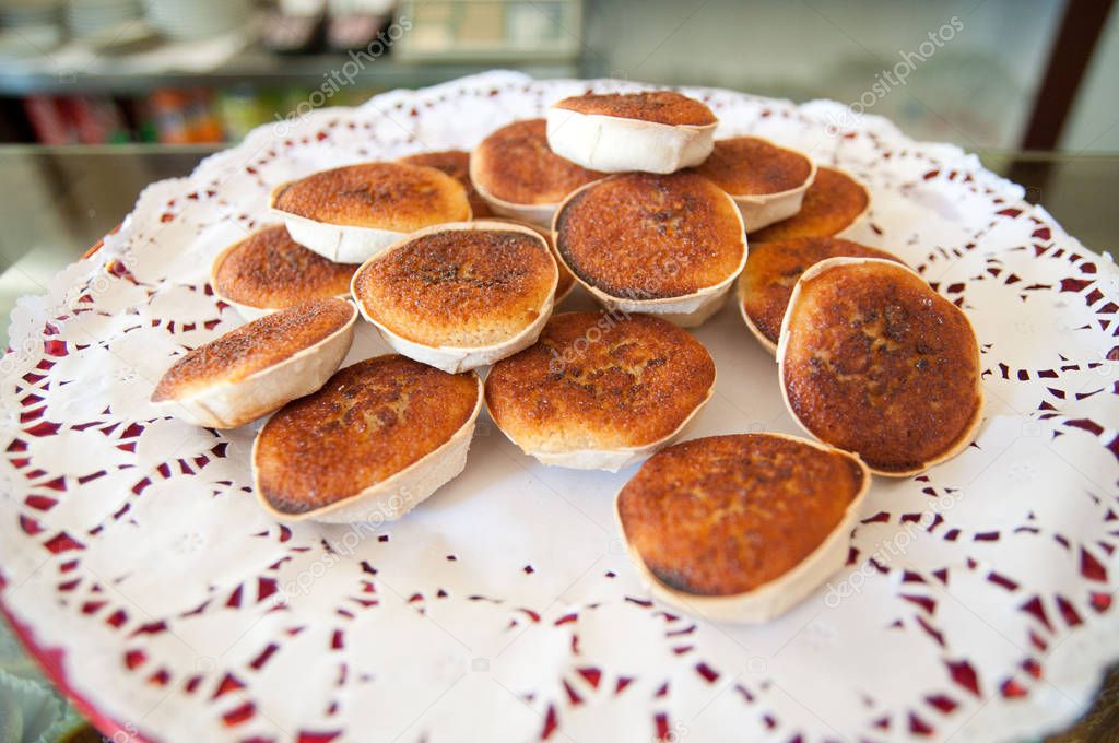 pile of tasty crisp pastry shells filled with marzipan-like mix of fresh cheese and sugar with flour on white napkin 