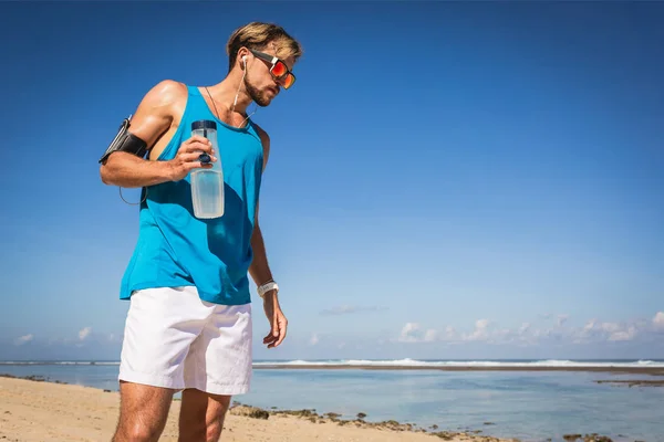 Hombre Atlético Con Brazalete Sosteniendo Botella Deportiva Playa — Foto de Stock