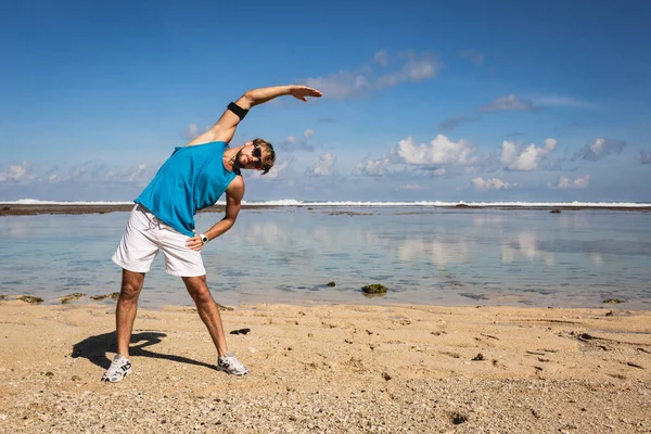 Uomo Atletico Abbigliamento Sportivo Che Estende Sulla Spiaggia Vicino Mare — Foto Stock