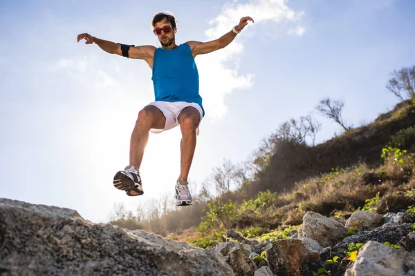 Undersidan Atletisk Man Hoppa Från Klippor Med Solljus — Gratis stockfoto