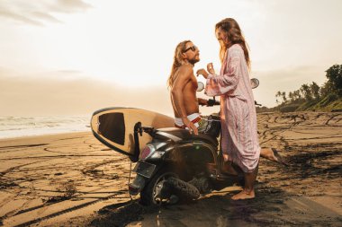 gün batımı sırasında çift ayakta Bali, Endonezya-scooter üzerinde beach yakınındaki yan görünüm