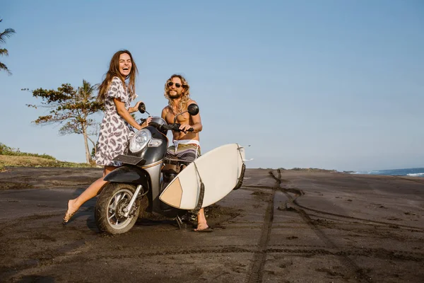 在印尼巴厘岛的海滩上玩滑板车和冲浪板的笑情侣 — 免费的图库照片