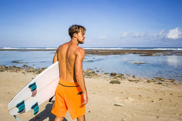 Back view of surfer with surfing board standing on sandy beach on summer day — Stock Photo