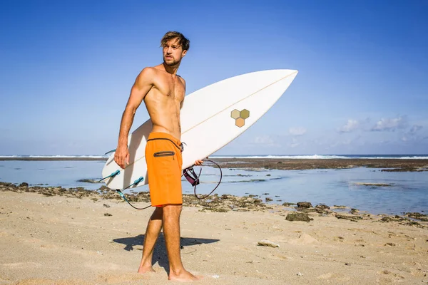 Jovem surfista com prancha de surf em pé na praia de areia no dia de verão — Fotografia de Stock